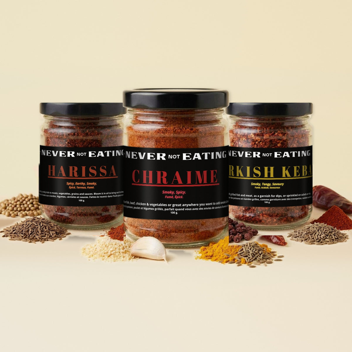 Never Not Eating Bring the Heat Trio: Harissa, Chraime and Turkish Kebab spice jars on a cream table with dried chillies
